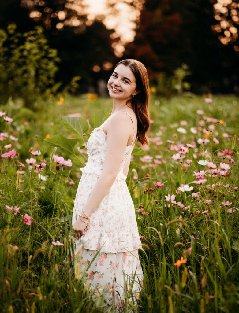 Senior portrait of girl twirling in a flower field at sunset in Oswego, IL – Naperville and Aurora senior photographer.