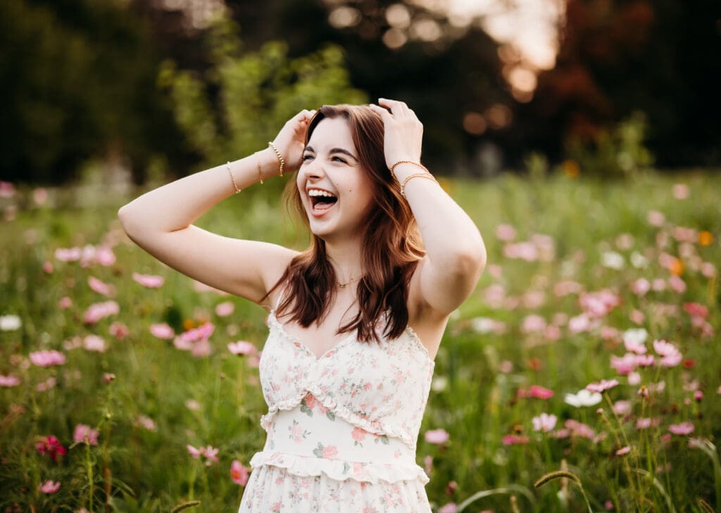 Senior girl standing in wildflower field at sunset, laughing – Chicago suburbs senior photographer.