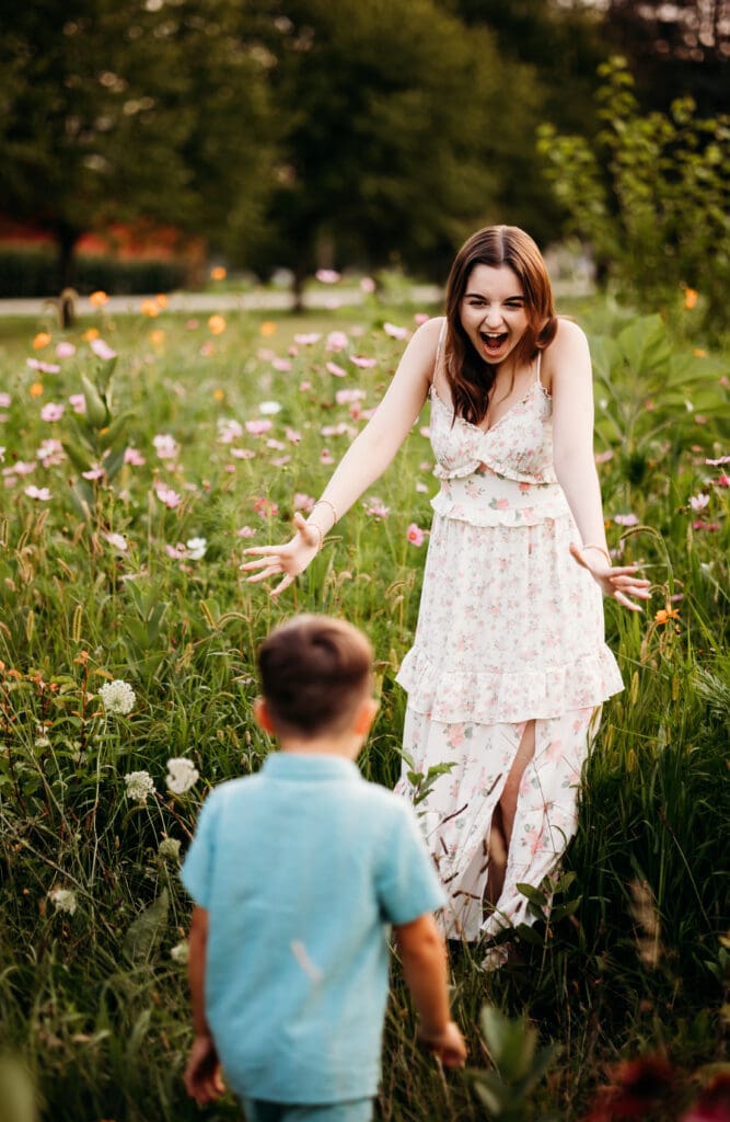 Senior girl in floral dress spinning a young boy during sunset – heartfelt sibling bond captured by Chicago suburbs photographer.