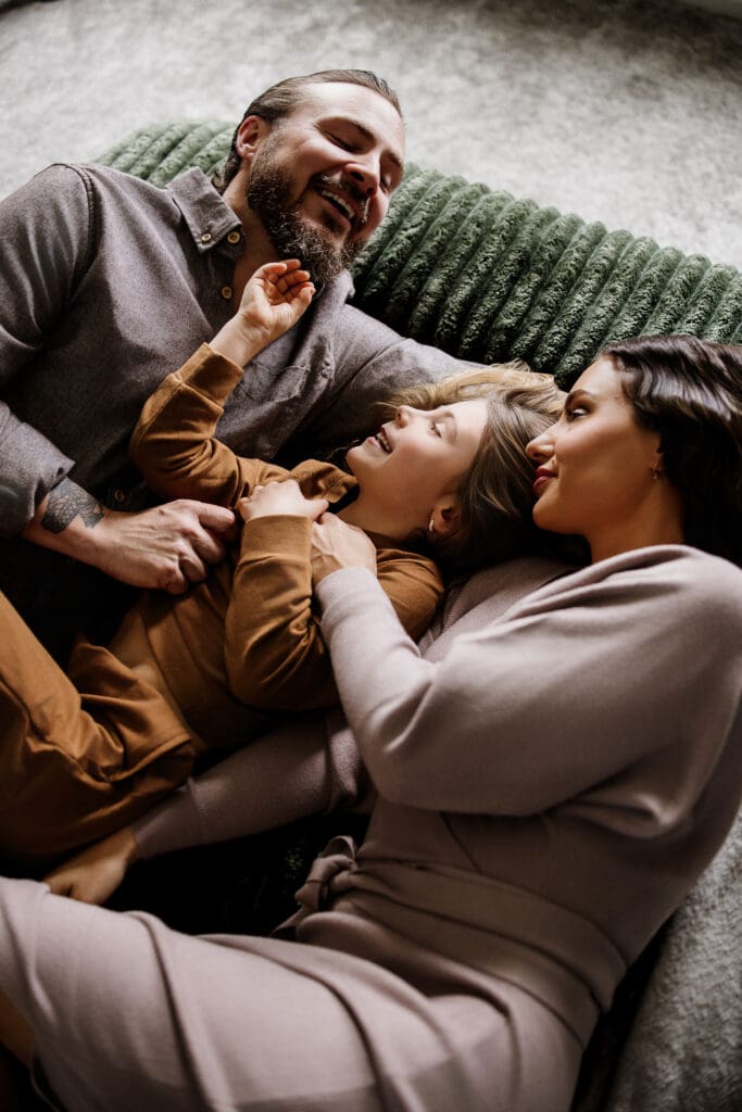 Family of three lying close together during an intimate in-home lifestyle session by Graceful Joy Photography Chicago, IL