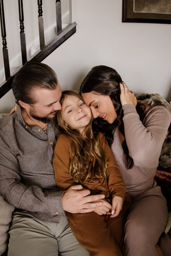Family of three lying close together during an intimate in-home lifestyle session by Graceful Joy Photography Oswego IL