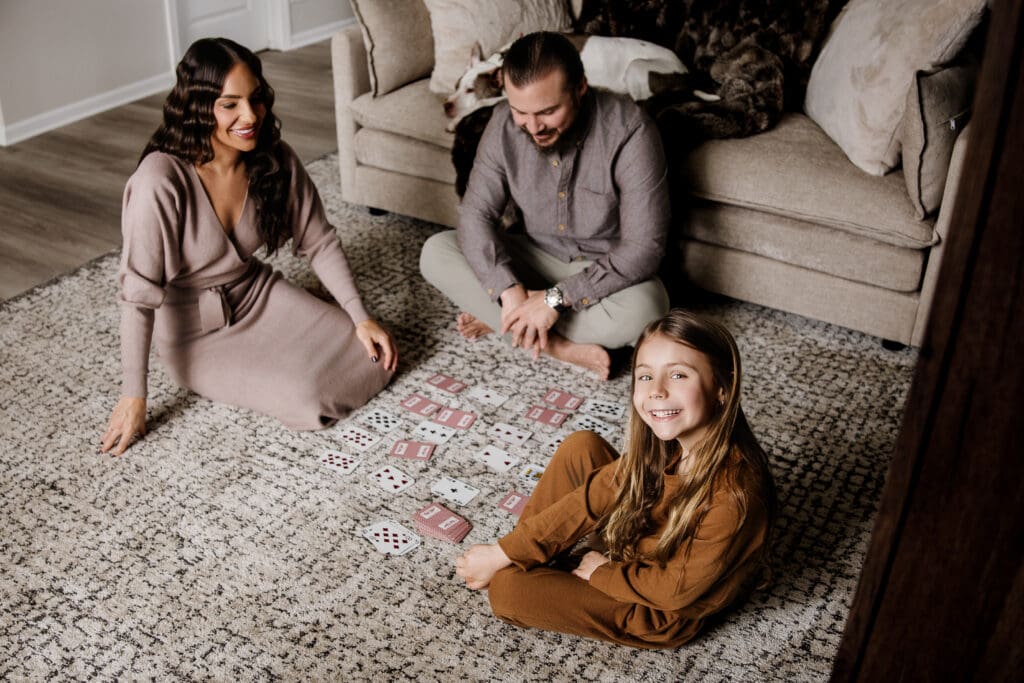 Family playing cards on the living room floor with their dog during an in-home lifestyle photography session in Chicago suburbs
